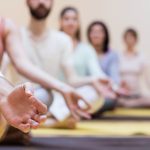 Group of people doing meditation on exercise mat